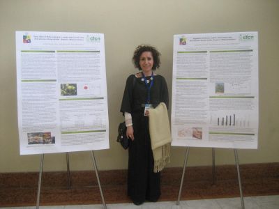 Profesora Amanda Huerta junto a los pósteres que presentó.