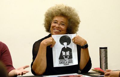 Angela Davis junto al afiche de la FECh de 1971, que exigía su libertad de la prisión.