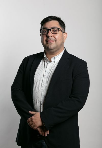 Profesor Alejandro Morales posa detrás de un fondo blanco tipo estudio