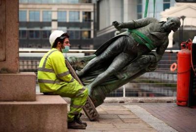 Un trabajador descansa después de que la estatua del dueño de esclavos Robert Milligan fuera derribada, en West India Quay, este de Londres. 